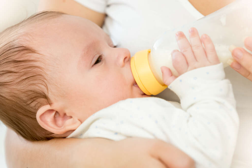 Portrait of cute 3 months old baby boy drinking milk from bottle